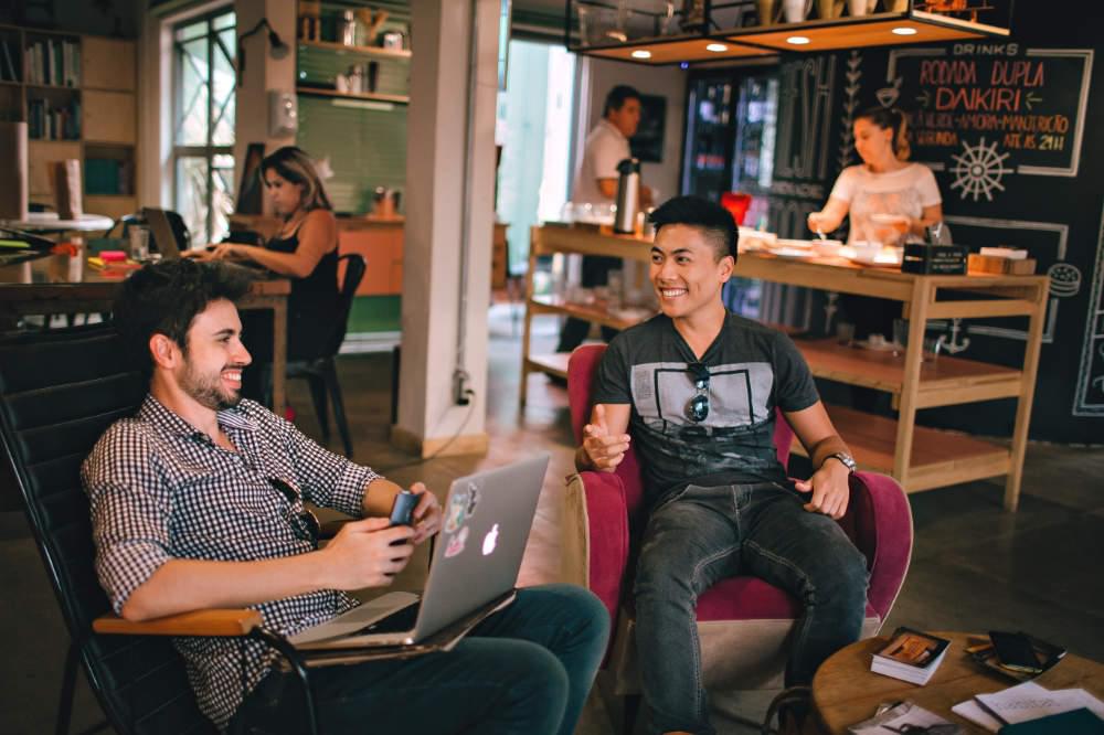 happy co-workers sitting with laptops on comfy chairs